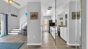 Eine moderne Küche mit weißen Schränken, Holzboden und einer Treppe, die zu einem Balkon führt.