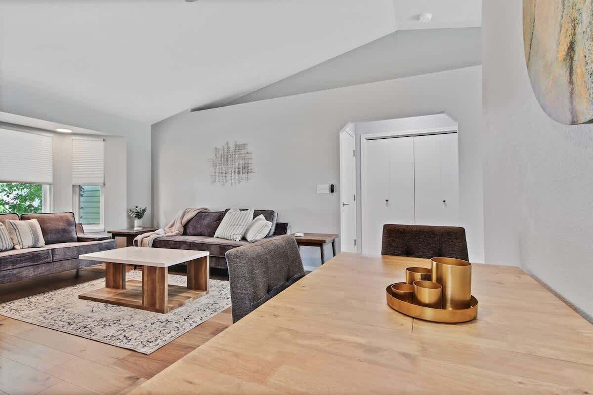 Un salon spacieux avec un canapé, une table basse et une table à manger sur laquelle est disposée une collection de coupes dorées.