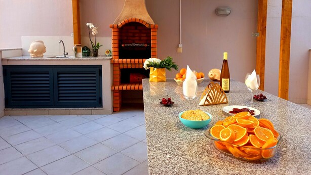 Una cocina con horno de ladrillo integrado, un lavamanos y una encimera con diversos alimentos y una botella de vino.