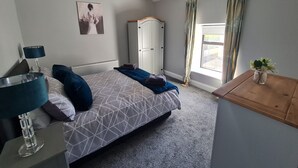 A bedroom with a bed, a wardrobe, a window with curtains, and a small table with a plant. - Amy's Place Charming 3 Bed House Donegal (Stranorlar)
