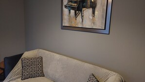 A living room with a grey sofa, patterned cushions, and a framed abstract painting on the wall. - Amy's Place Charming 3 Bed House Donegal (Stranorlar)