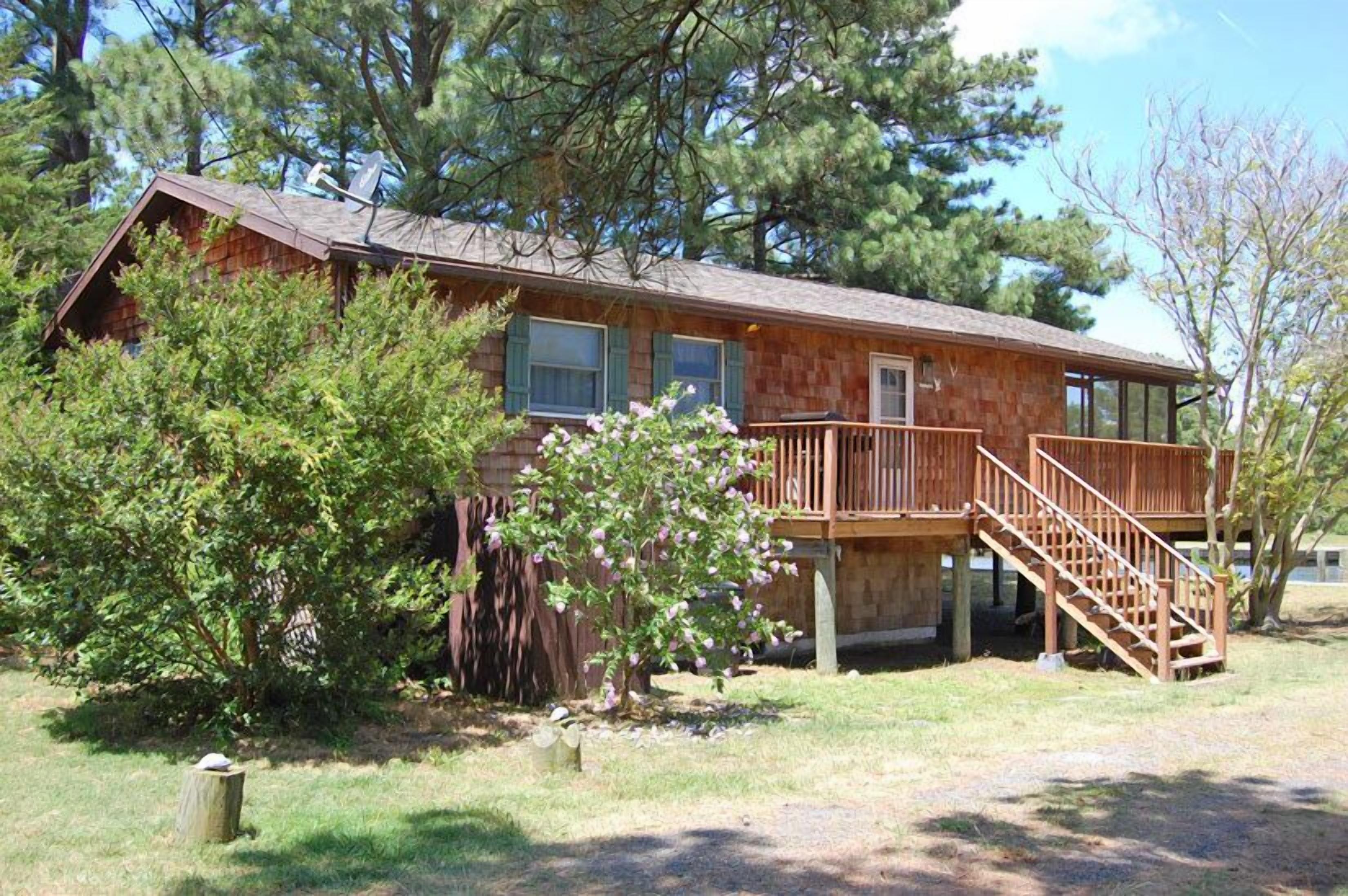 A wooden cabin with a balcony and a staircase leading to the entrance.