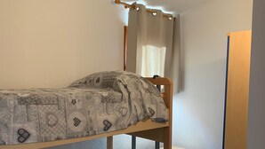 Een stapelbed met beddengoed met een patroon en een gordijn.