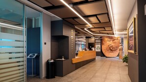 En moderne reception med skranke, glasdøre og en stor vægskulptur.