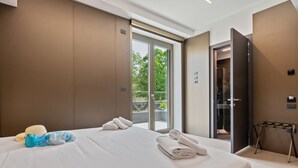 Et hotelværelse med en stor seng, badeværelse og en balkon med udsigt til træer.