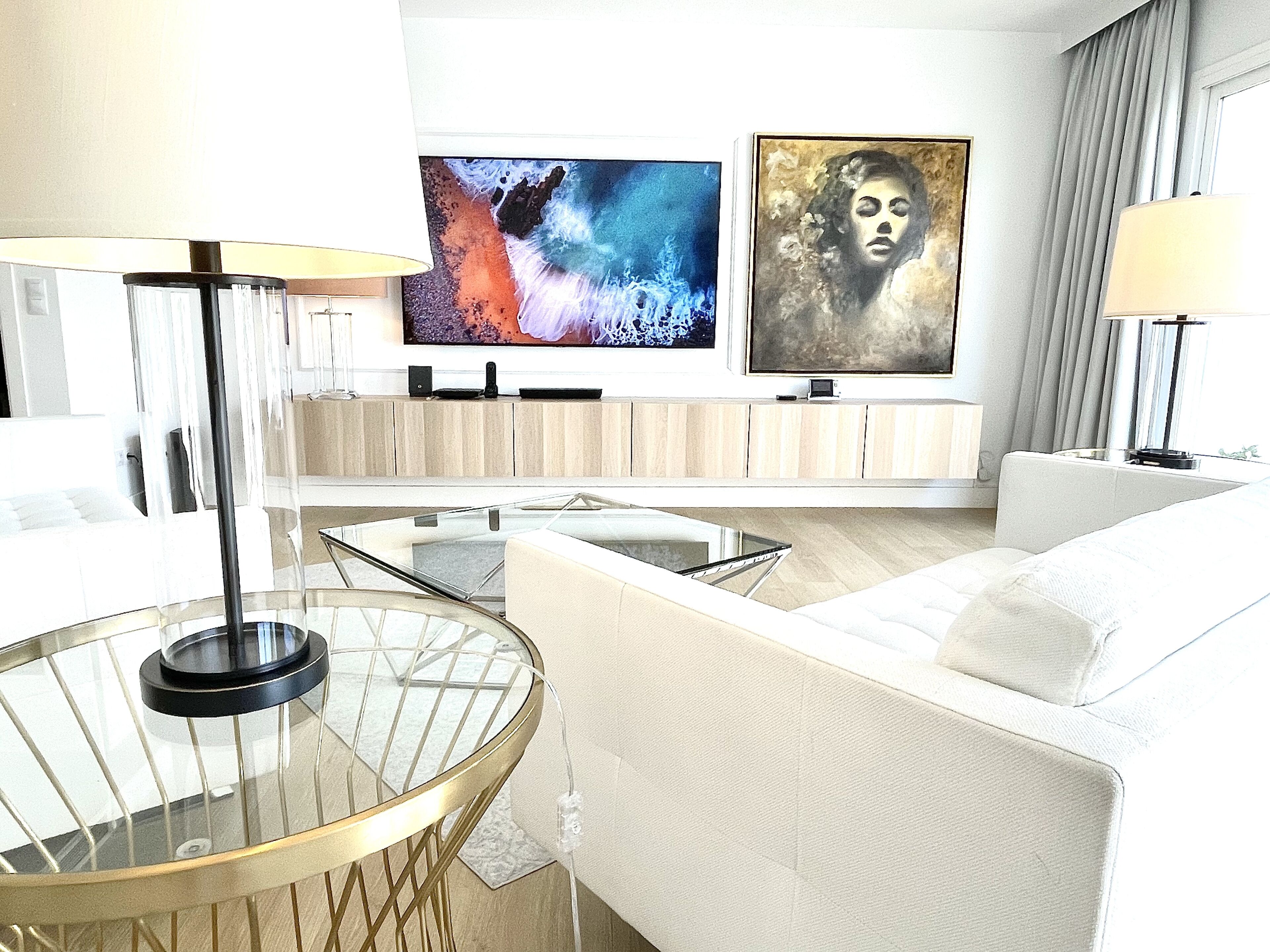 Ein modernes Wohnzimmer mit einem Glastisch, einer Couch und Kunstwerken an der Wand.