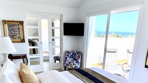 Une chambre avec un lit, une télévision, une fenêtre donnant sur un beau paysage et un fauteuil.