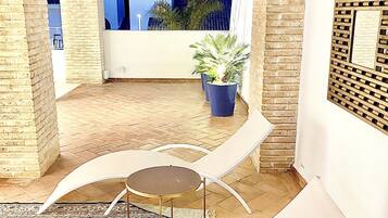 An outdoor seating area with a table and chairs, a potted plant, and a view of the sky.