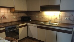 Een kleine keuken met een magnetron, spoelbak, vaatwasser en oven.