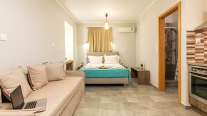 A modern bedroom with a bed, a sofa, a laptop, and an oven. - Georgia Apartments (Zakynthos)