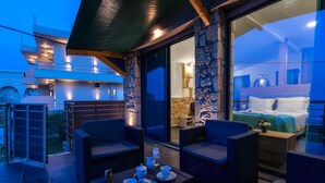 A modern outdoor seating area with wicker furniture and a table set for tea, overlooking a bedroom with a bed and nightstand. - Georgia Apartments (Zakynthos)