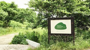 A sign for Yoichi Vineyard Glamping with a natural, green backdrop.