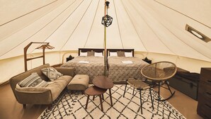 A tent-style room with two beds, a sofa, a chair, a small table, and a hanging light fixture. - Yoichi Vineyard Glamping (Yoichi)