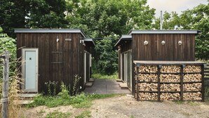 A rustic wooden cabin with a dirt path leading to a stack of firewood. - Yoichi Vineyard Glamping (Yoichi)