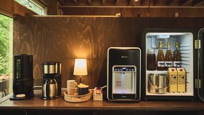 A kitchen counter with a coffee maker, a water dispenser, a lamp, and a refrigerator containing beverages and milk cartons. - Yoichi Vineyard Glamping (Yoichi)