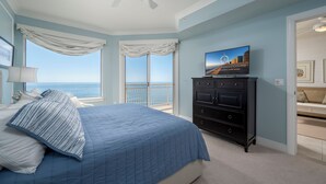 Un dormitorio con una cama grande, un televisor en una cómoda y vista al océano.