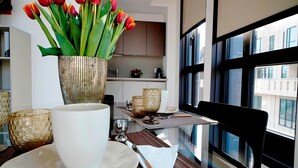 Ein stilvoller Essbereich mit einem Tisch für zwei Personen, inklusive einer Tulpenvase, einer weißen Tasse und strukturiertem Glas.