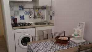 Une cuisine compacte équipée d’un lave-linge, d’un évier et d’un coin repas avec des chaises et une table.