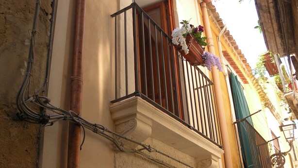 Un bâtiment doté d’un balcon, d’une porte en bois et d’une fenêtre ornée d’un vitrail décoratif.