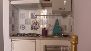 Une cuisine équipée d’une cuisinière à gaz, d’un évier et d’une table à manger sur laquelle se trouvent une bouteille de champagne et des verres.