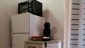 Une cuisine compacte avec un réfrigérateur blanc, un four à micro-ondes et un petit appareil noir posé sur le dessus.