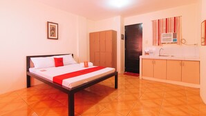 A hotel room with a bed, a wardrobe, a bathroom with a shower, and a sink. - Reddoorz @ FDB Homes Nueva Ecija (San Jose City)