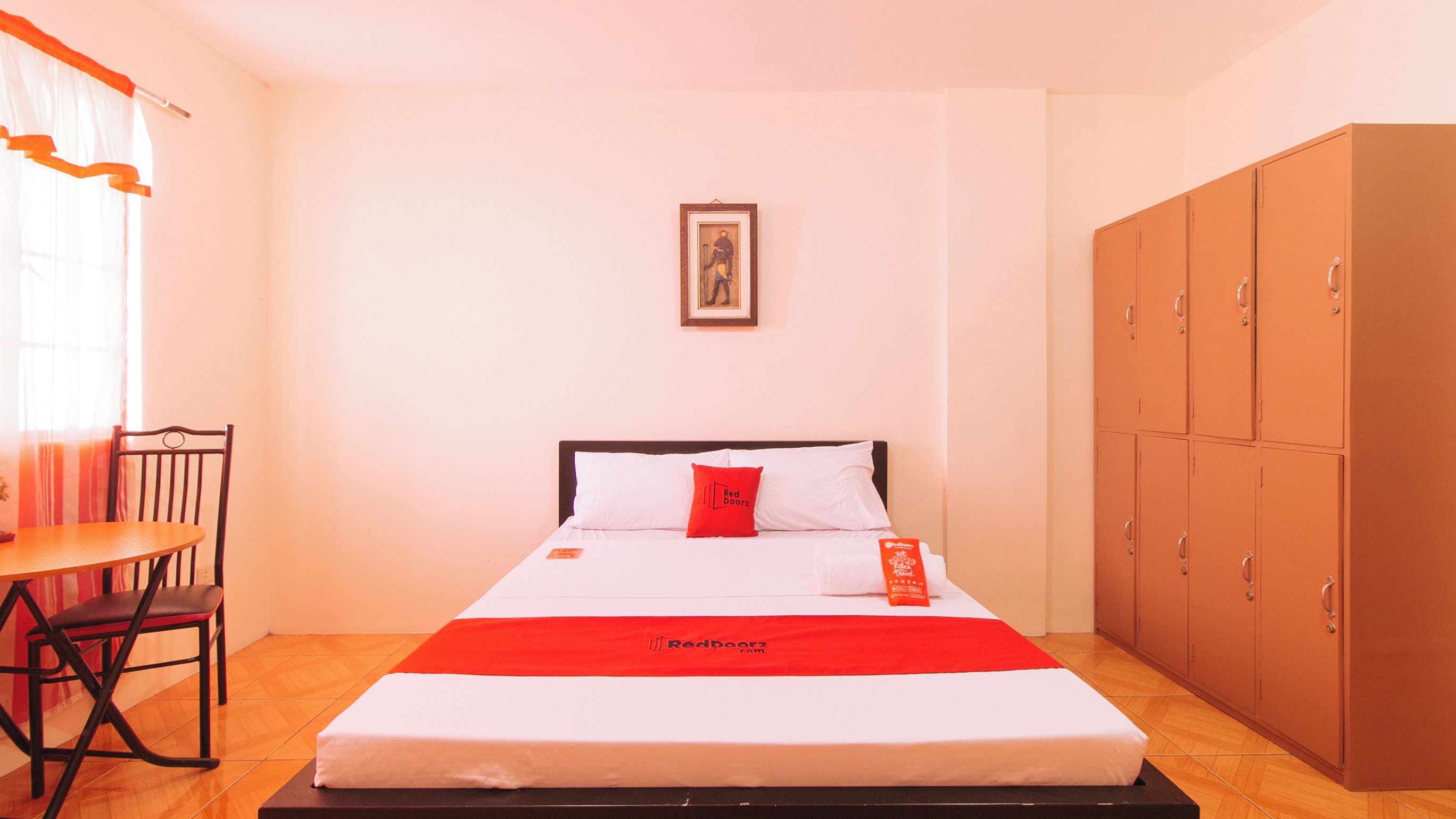 A hotel room with a bed, a chair, a desk, and a wardrobe.