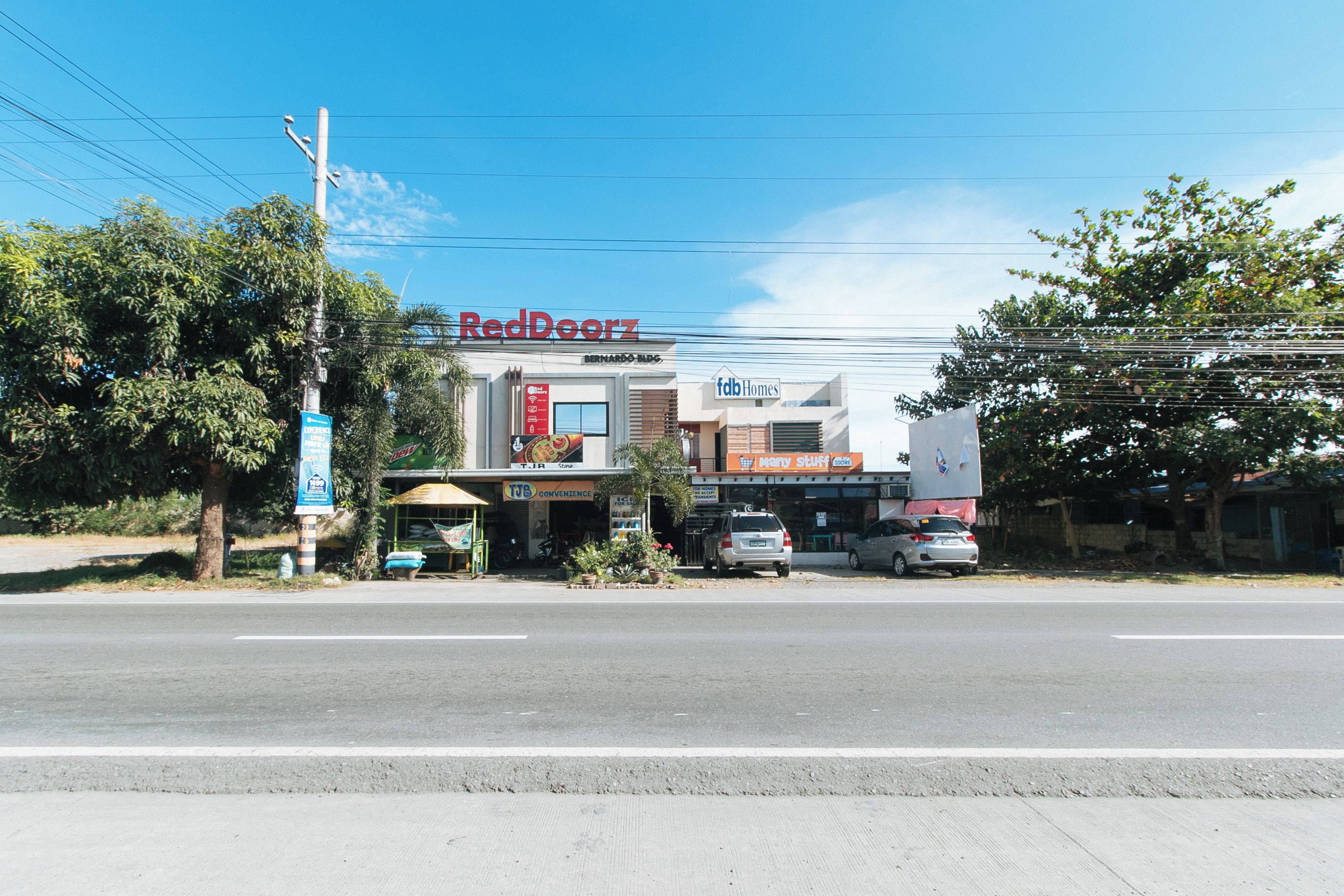 A commercial building with multiple storefronts, including RedDoorz and fdb Homes.