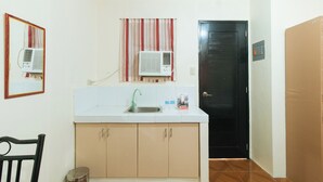 A small kitchen with a sink, cabinets, and an air conditioner. - Reddoorz @ FDB Homes Nueva Ecija (San Jose City)
