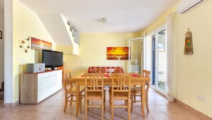 Un comedor con una mesa y sillas de madera, un televisor sobre un mueble y obras de arte en las paredes.