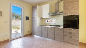 Una cocina moderna con estufa a gas, horno empotrado y puerta corrediza que da a un balcón.