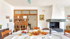 A dining area with a table set for a meal, a fireplace, and a wooden partition with shelves. - 2186 Attico Demetra (Avetrana)
