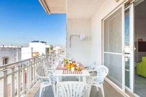A balcony with a dining table set for two, chairs, and a view of the cityscape.