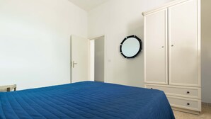 Une chambre à coucher avec un lit, une armoire et un miroir au mur.