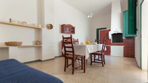 Une pièce comprenant un lit, une table à manger avec des chaises, un coin cuisine avec une cuisinière et des étagères remplies de divers objets.