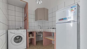 Une cuisine compacte équipée d’un lave-linge, d’un réfrigérateur et d’un évier.