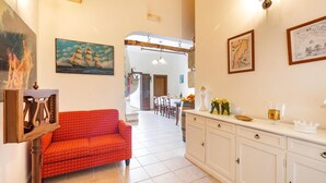 Ein Wohnzimmer mit einem rot gemusterten Sofa, weißen Schränken und an der Wand befestigter Kunst.