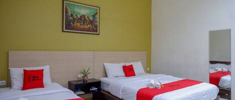 Habitación de hotel con dos camas, un cuadro en la pared y una mesita de noche con una planta.