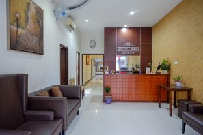 A hotel lobby with a reception desk, sofas, and a painting on the wall. - Reddoorz Plus @ Hotel Asih UNY (Depok)