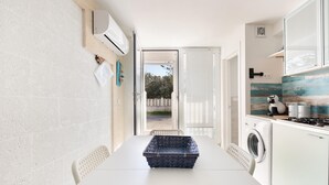 Una cocina compacta con lavadora, una mesa de comedor y una cesta.