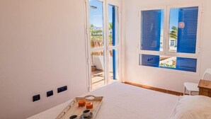 A bedroom with a bed, a tray with drinks, and a view of the outside.