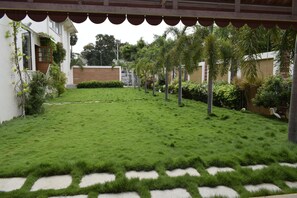 Un jardín bien cuidado con césped, sendero de piedra y palmeras.