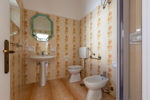 Une salle de bain équipée d’un lavabo, de toilettes, d’un bidet et d’un miroir.
