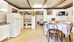Une cuisine équipée d’un réfrigérateur, un coin repas avec une table et des chaises, et un téléviseur fixé au mur.