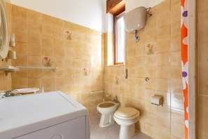 A bathroom with beige tiles, a toilet, a bidet, a sink, and a mirror. - 2219 Villa Cesarina (Porto Cesareo)
