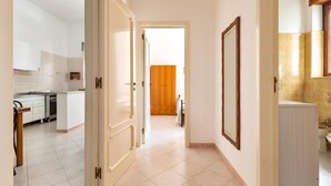 Een gang die leidt naar een slaapkamer met een houten deur, een radiator en een badkamer met toilet en wastafel.