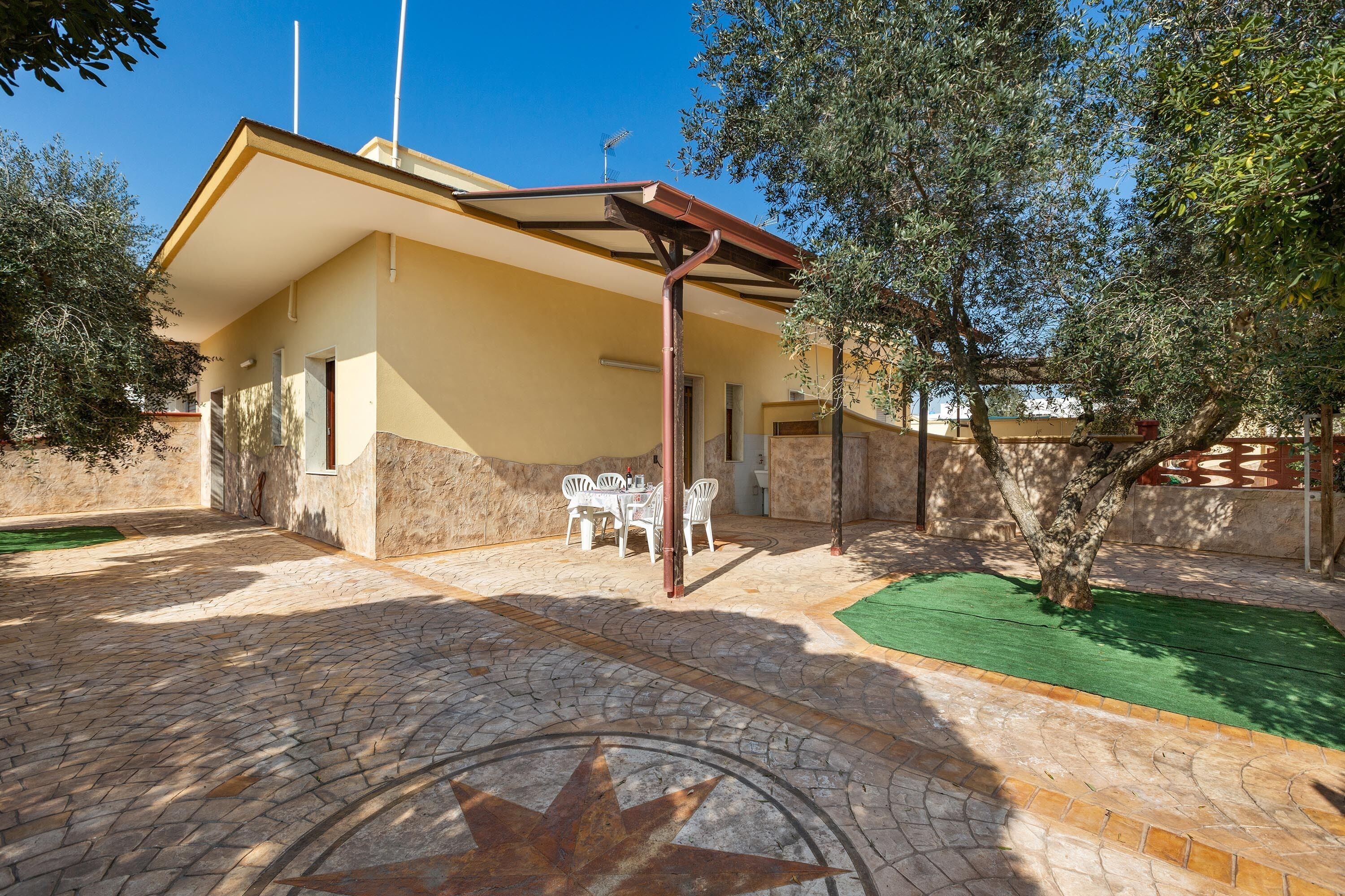 Un bâtiment doté d’un patio couvert, d’un espace extérieur aménagé pour s’asseoir et d’une cour pavée.