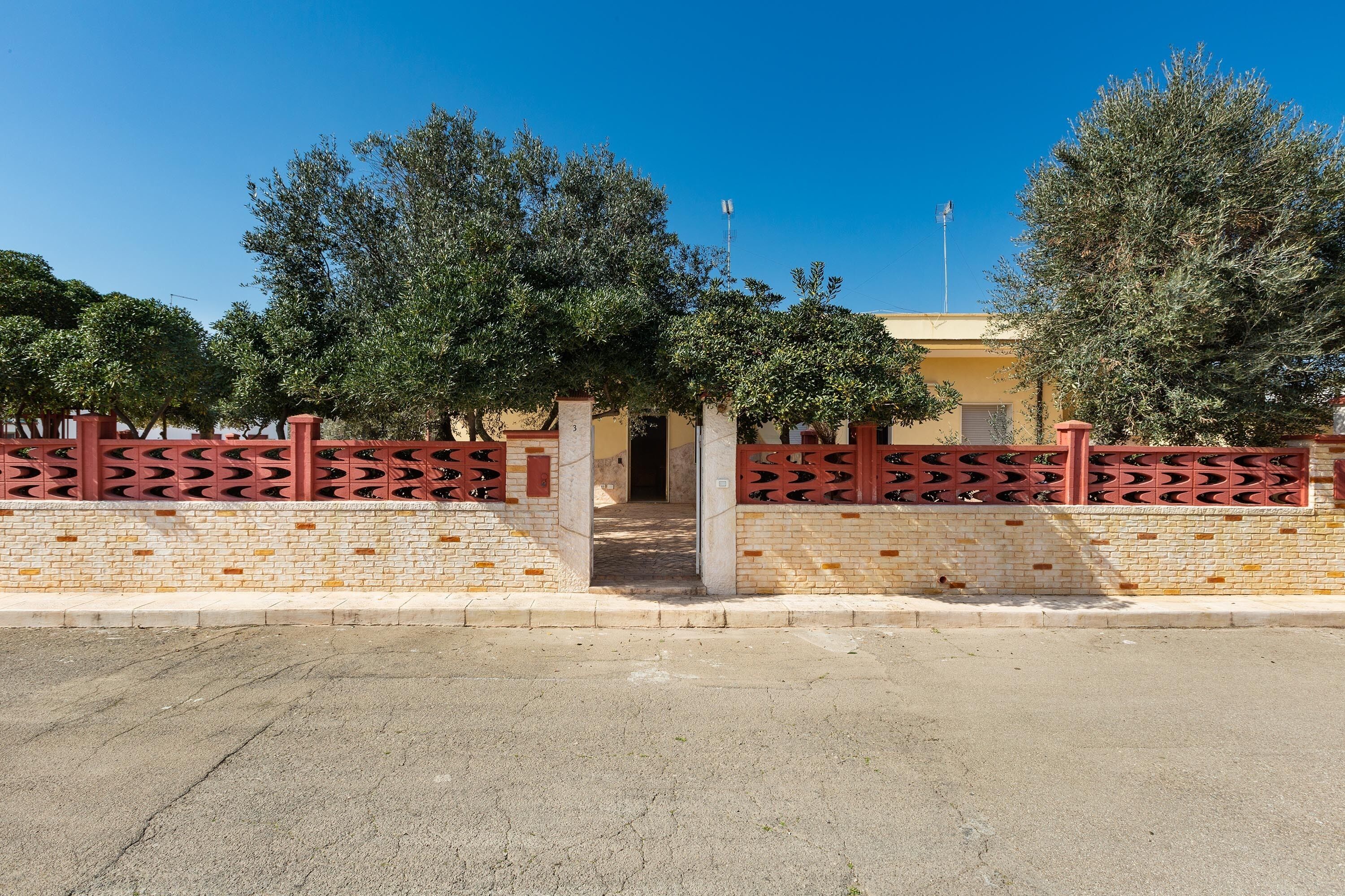 A building with a brick facade, a red gate, and trees in the background.