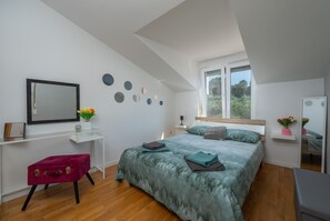 A bedroom with a bed, a desk, a chair, a window, and wall decorations.
