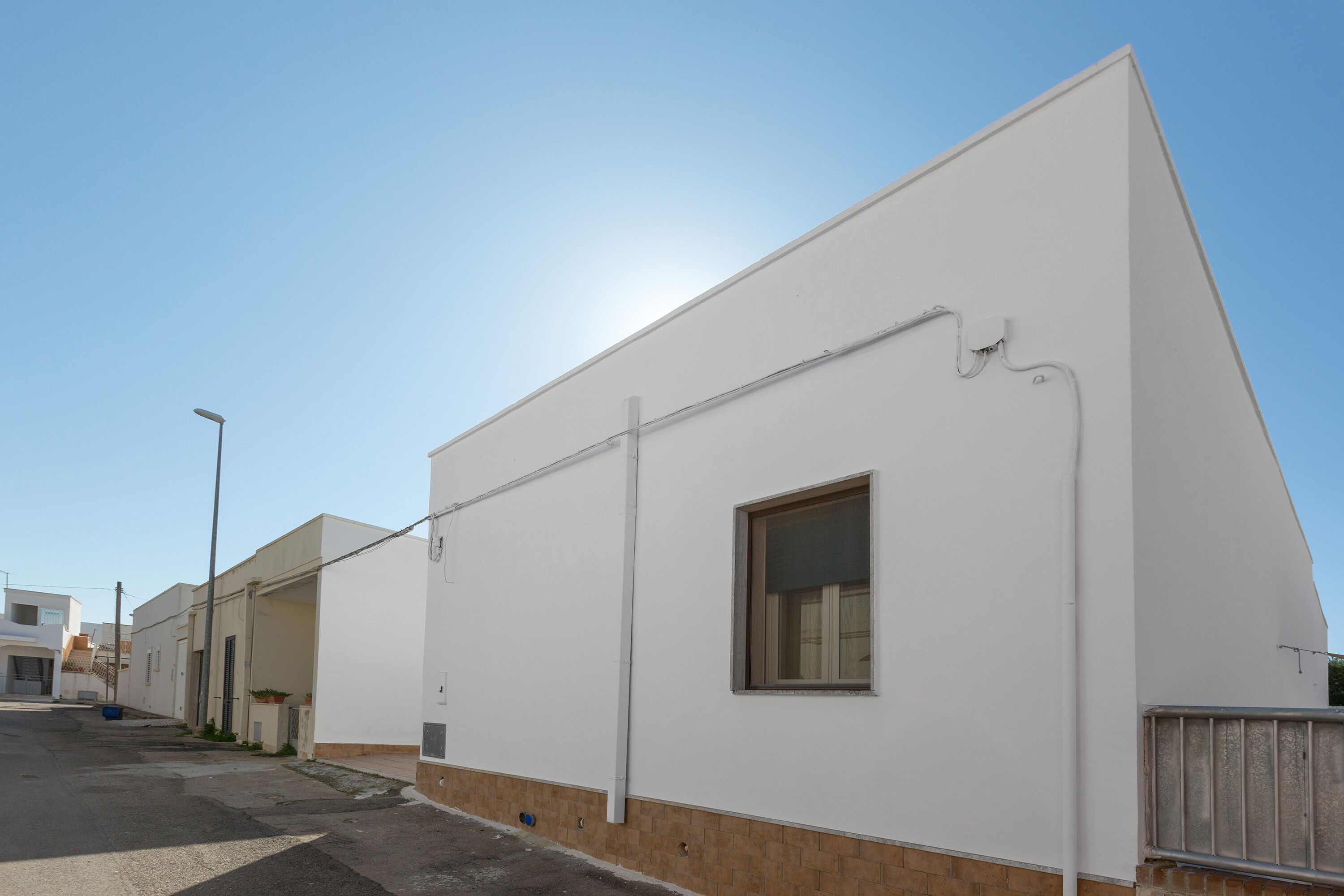A modern building with a flat roof, a small window, and a visible utility pipe.